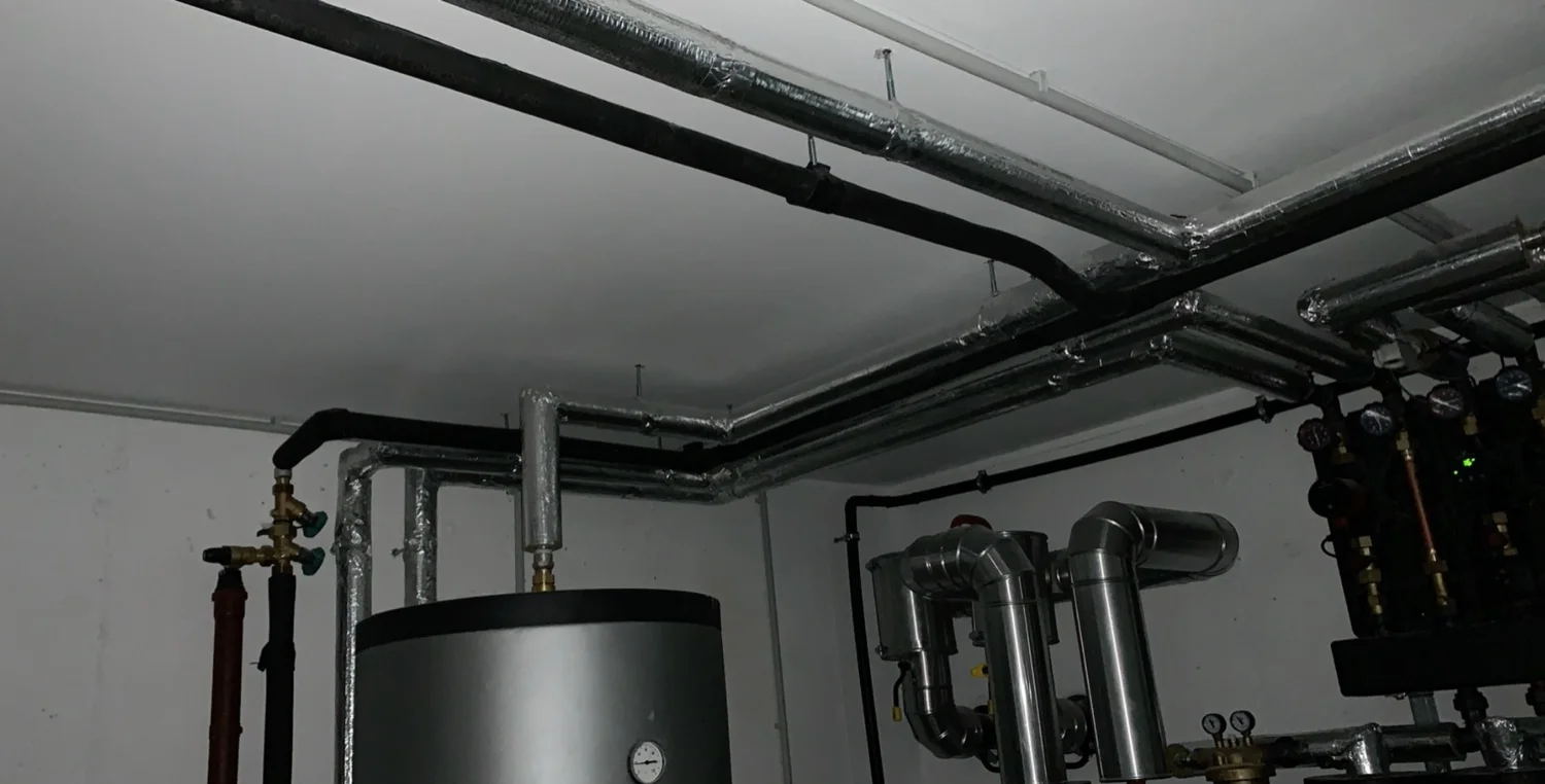 Heizzentrale mit Pufferspeicher und gedämmten Rohrleitungen in einem Heizraum