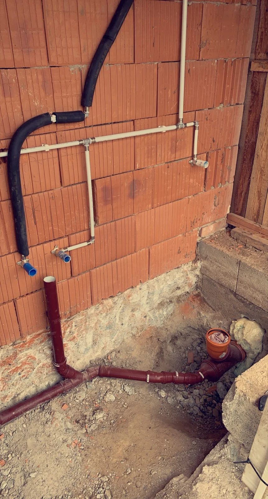 Neu verlegte Wasser- und Abflussleitungen in einer Ziegelwand im Rohbau